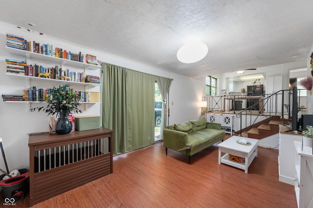 living room with wood finished floors, a textured ceiling, and stairway