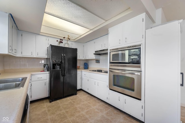 kitchen with black appliances, a sink, under cabinet range hood, light countertops, and decorative backsplash
