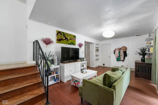 living room with stairs, dark wood-style floors, and a textured ceiling