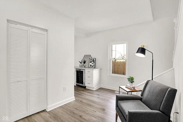 sitting room with beverage cooler, light wood finished floors, a dry bar, and baseboards