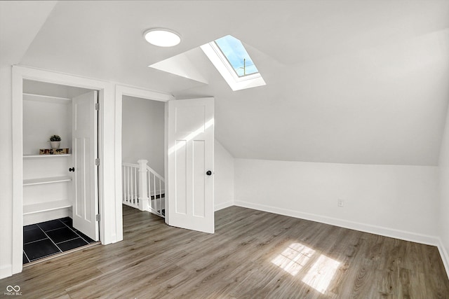 additional living space featuring a skylight, lofted ceiling, wood finished floors, and baseboards