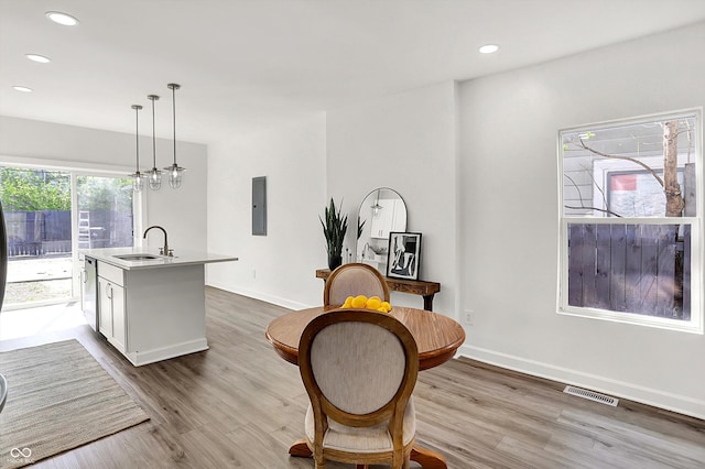 dining space with light wood-style flooring, recessed lighting, baseboards, and electric panel