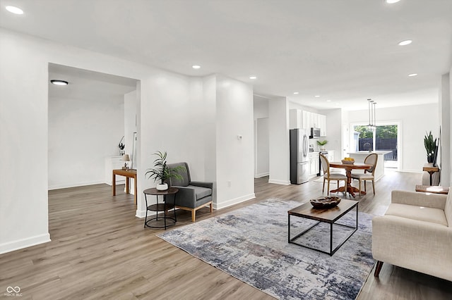 living area with baseboards, light wood-style floors, and recessed lighting