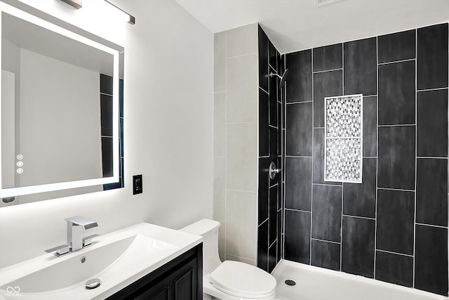 full bathroom with toilet, vanity, and a tile shower