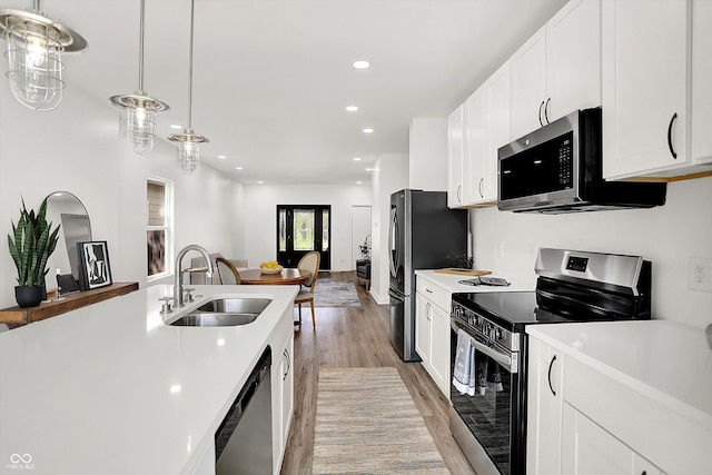 kitchen featuring stainless steel appliances, a sink, light wood finished floors, light countertops, and recessed lighting