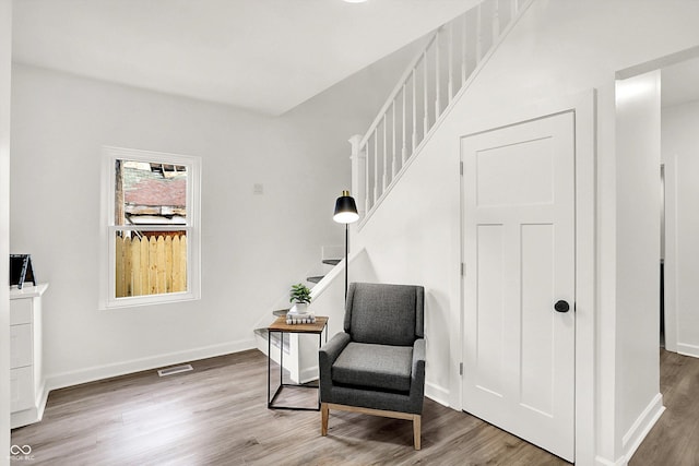 living area featuring wood finished floors, baseboards, and stairway