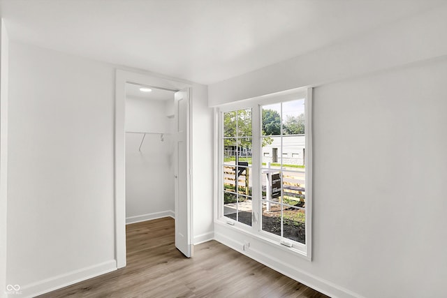 unfurnished bedroom featuring a closet, baseboards, wood finished floors, and a spacious closet