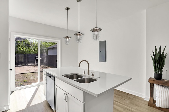 kitchen featuring a sink, light wood-type flooring, stainless steel dishwasher, light countertops, and an island with sink