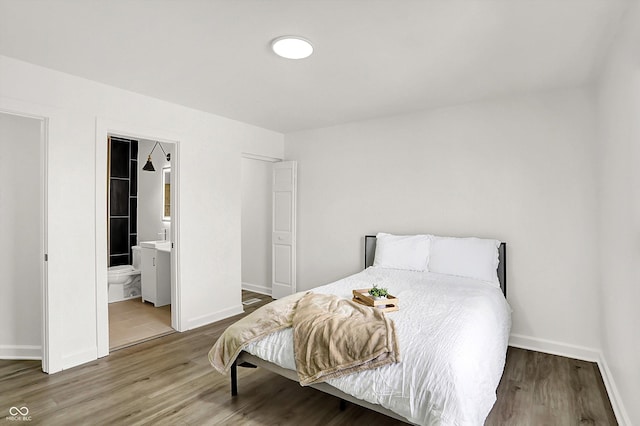 bedroom featuring wood finished floors, baseboards, and ensuite bath