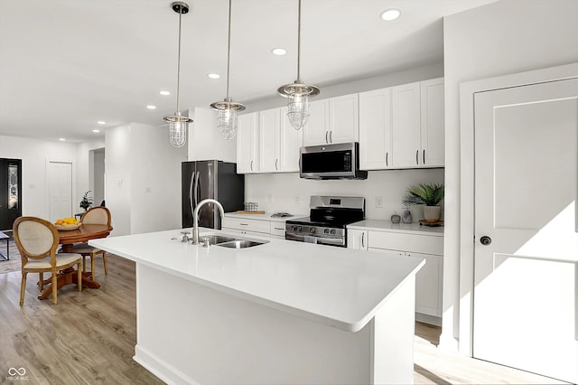kitchen featuring appliances with stainless steel finishes, a sink, light wood-style floors, recessed lighting, and white cabinetry