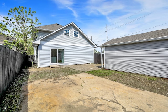 back of house featuring a fenced backyard, a patio, and a shingled roof