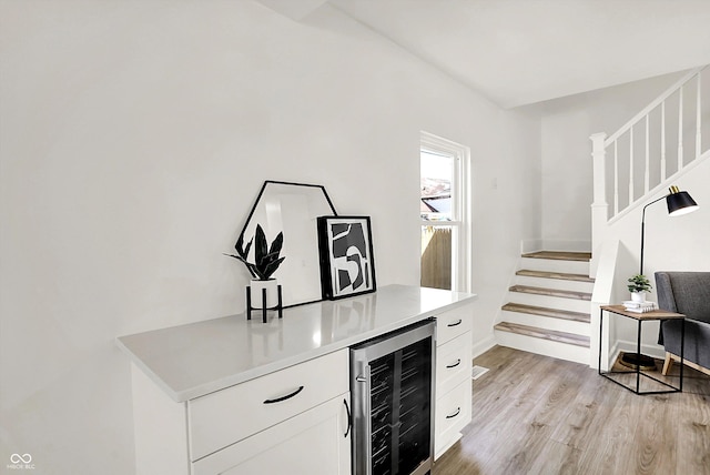 indoor dry bar with wine cooler, stairway, light wood finished floors, and baseboards