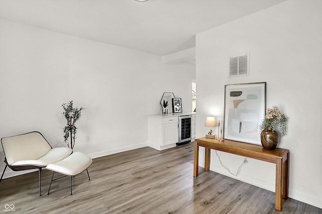 living area featuring beverage cooler, light wood-style flooring, and baseboards