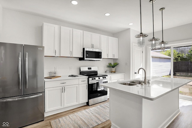 kitchen featuring appliances with stainless steel finishes, a sink, light wood-style floors, light countertops, and recessed lighting