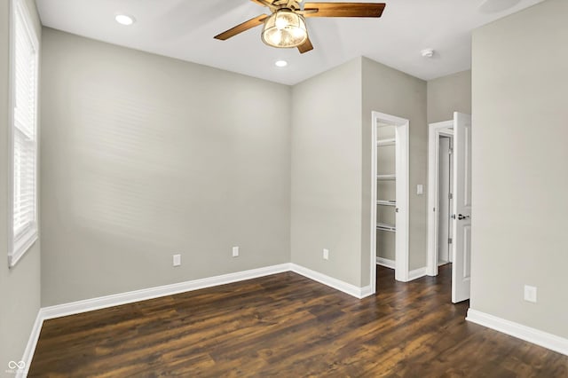 6153 Dugan Dr, Whitestown, IN 46075 - unfurnished bedroom with a walk in closet, baseboards, dark wood-type flooring, ceiling fan, and a closet