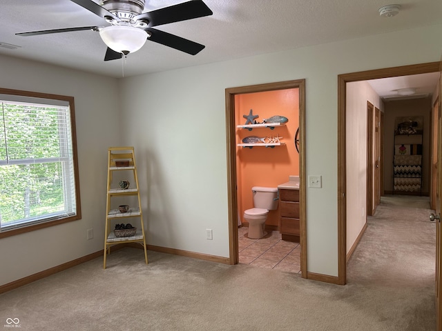 bedroom with light colored carpet, baseboards, and ensuite bathroom
