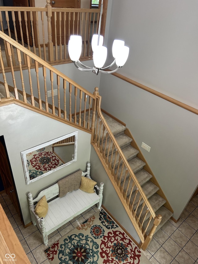 stairway with a chandelier, tile patterned flooring, and baseboards