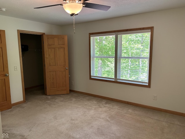 unfurnished bedroom with a spacious closet, light colored carpet, and multiple windows