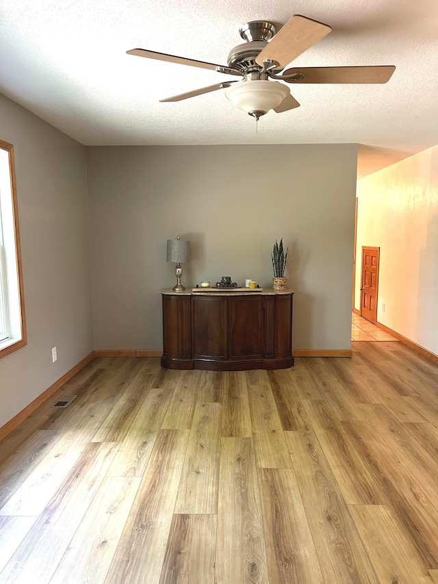 unfurnished room featuring a ceiling fan, light wood finished floors, and baseboards