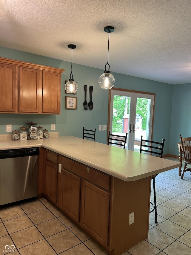 kitchen with stainless steel dishwasher, a peninsula, light countertops, light tile patterned flooring, and french doors