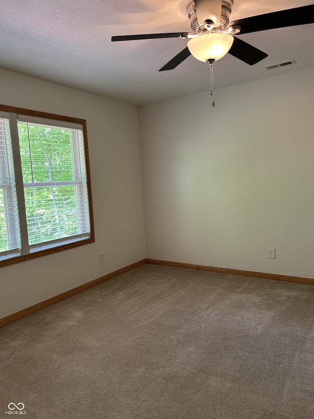 spare room featuring light carpet, a textured ceiling, a ceiling fan, and baseboards