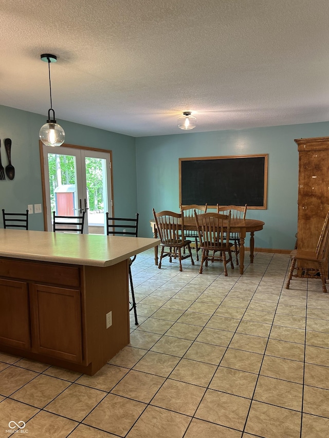 kitchen with light countertops, light tile patterned flooring, a textured ceiling, hanging light fixtures, and french doors
