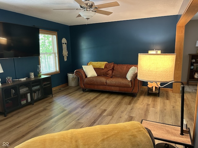 living area with a ceiling fan, wood finished floors, and baseboards