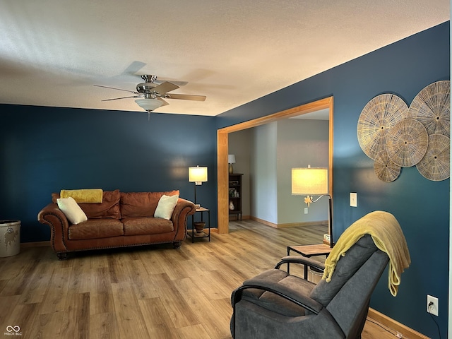 living room with baseboards, a ceiling fan, and wood finished floors