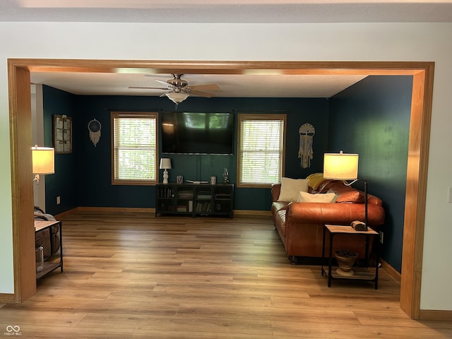 living room featuring healthy amount of natural light, light wood-type flooring, ceiling fan, and baseboards