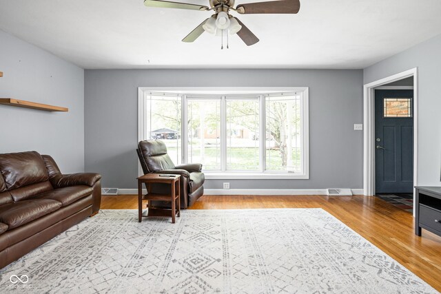 living area with ceiling fan, baseboards, and wood finished floors