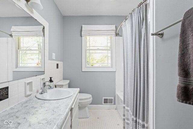 bathroom featuring toilet, vanity, tile patterned floors, shower / bath combination with curtain, and baseboards