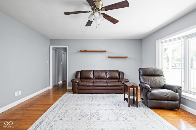living area featuring wood finished floors, baseboards, and ceiling fan
