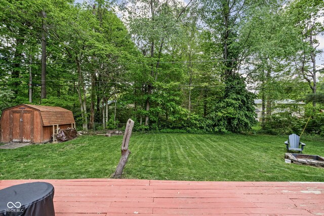 view of grassy yard with a shed, a deck, and an outdoor structure