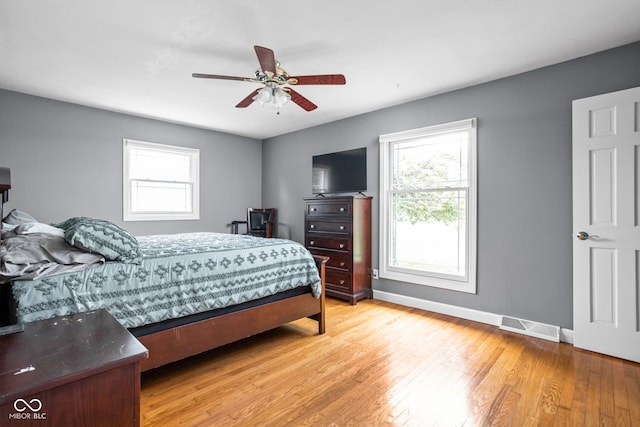 bedroom featuring multiple windows, light wood finished floors, baseboards, and ceiling fan