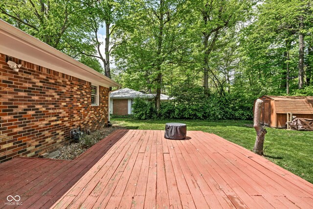 wooden terrace featuring a storage shed, a yard, and an outbuilding