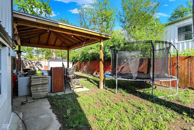 fenced backyard featuring a trampoline and a gazebo