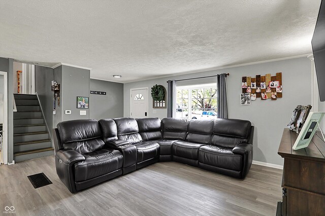 living area featuring wood finished floors, stairway, a textured ceiling, baseboards, and crown molding