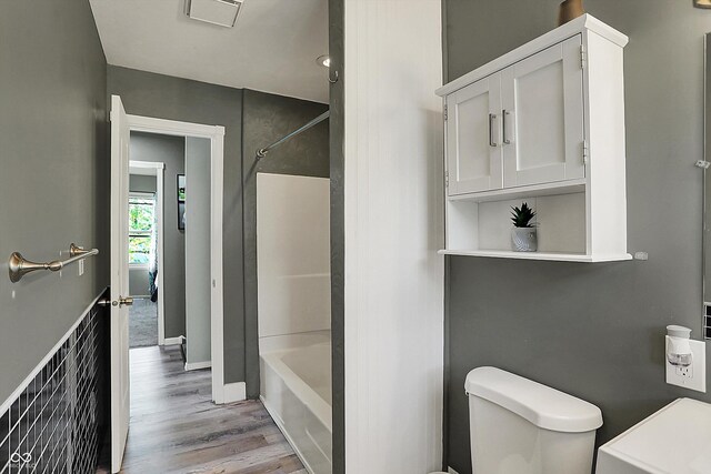 full bathroom with wood finished floors, toilet, bathtub / shower combination, and baseboards