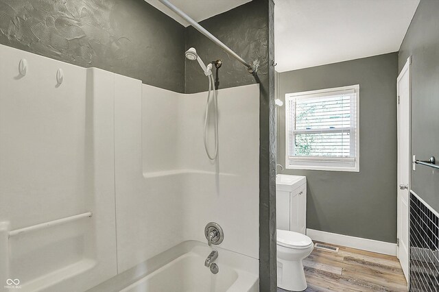 full bath with wood finished floors, toilet, shower / washtub combination, and baseboards