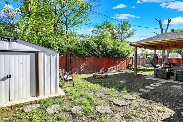 fenced backyard with a trampoline, a storage unit, a gazebo, an outbuilding, and outdoor lounge area