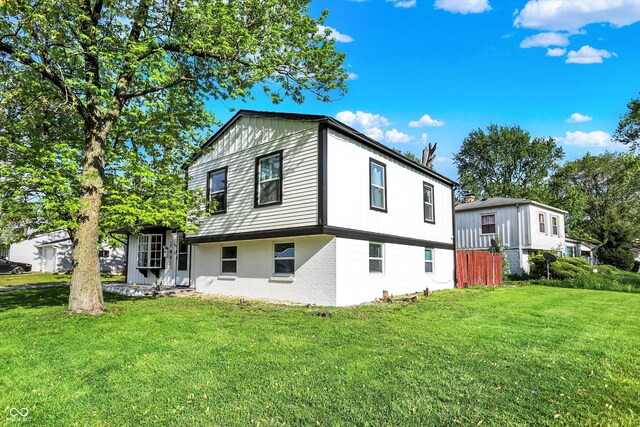 back of house featuring brick siding and a yard