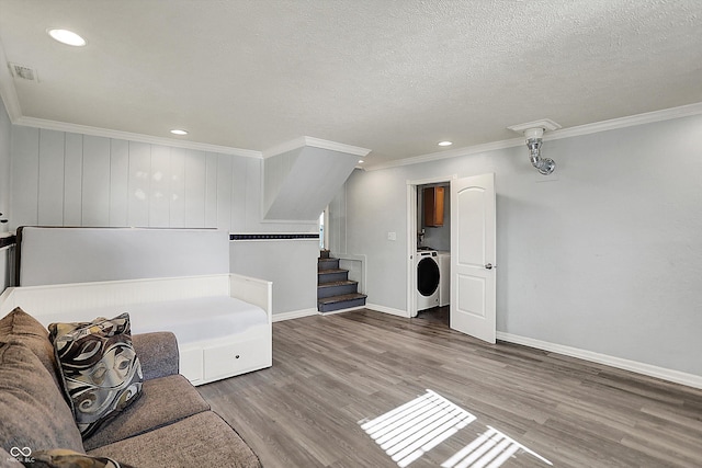 unfurnished room with washer / clothes dryer, wood finished floors, baseboards, ornamental molding, and stairs