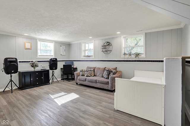 living area with wood finished floors, ornamental molding, a textured ceiling, and a desk