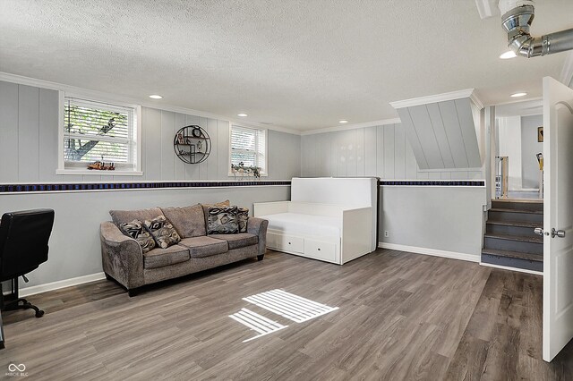 living room with a textured ceiling, crown molding, healthy amount of natural light, wood finished floors, and stairway