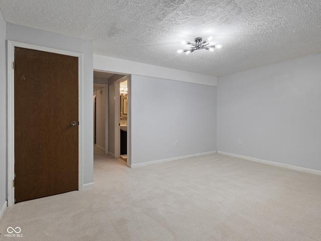 unfurnished room featuring light carpet, baseboards, and a textured ceiling