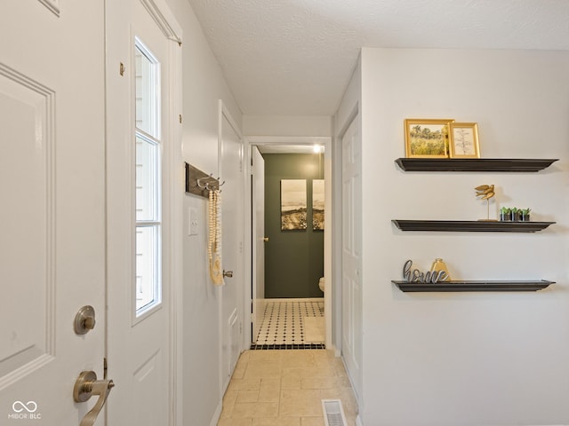 hall featuring a textured ceiling and baseboards