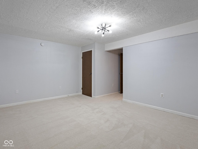 unfurnished room with a textured ceiling, light carpet, and baseboards