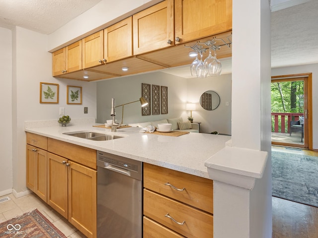kitchen featuring dishwasher, a sink, a textured ceiling, light stone countertops, and a peninsula