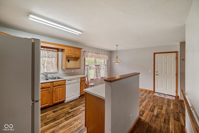 kitchen featuring white appliances, dark wood finished floors, light countertops, a kitchen island, and decorative light fixtures