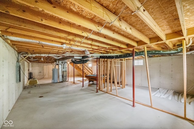 unfinished basement with gas water heater, stairway, and electric panel